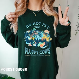 Pu&ograve; includere: Felpa verde bosco con una grafica colorata di un bisonte con montagne e il testo "Do Not Pet The Fluffy Cows - Nature Enthusiast".