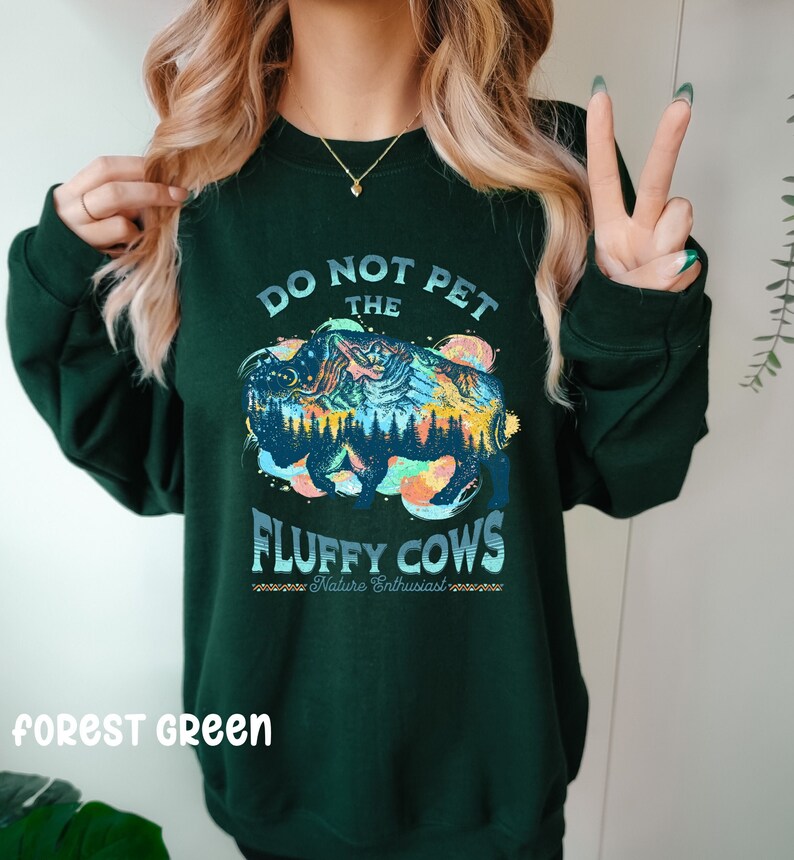 Pu&ograve; includere: Felpa verde bosco con una grafica colorata di un bisonte con montagne e il testo "Do Not Pet The Fluffy Cows - Nature Enthusiast".