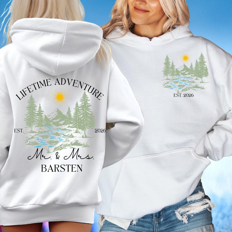 May include: White hoodie with a nature-themed design. The front features a mountain and tree graphic with the text "EST. 2026". The back displays "LIFETIME ADVENTURE" above a similar graphic, with "Mr. & Mrs. BARSTEN" below.