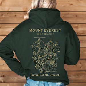 May include: A dark green hoodie with a graphic print of Mount Everest. The print includes the mountain's elevation in meters and feet, "Summit of Mt. Everest 8848", and a map of the mountain with various campsites and locations.
