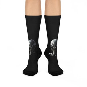May include: A pair of black socks with a grey alien graphic on each sock.