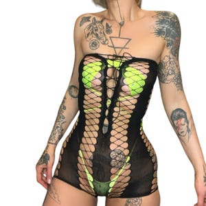 May include: Black fishnet bodysuit with a lace-up front and green accents. The bodysuit has a revealing design with cutouts and a low neckline.