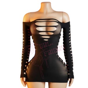 May include: Black off-the-shoulder dress with long sleeves and cut-out details. The dress features multiple horizontal cut-outs across the chest and vertical cut-outs along the sleeves and sides. The text "GRL FRIDAY" is printed on the dress.