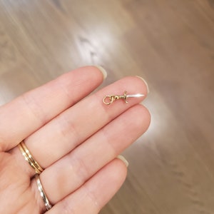 Peut inclure: Un charme en or en forme de dague argent&eacute;e avec une boucle dor&eacute;e pour l'attacher &agrave; un collier ou un bracelet.