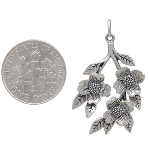 May include: Silver pendant charm featuring a stylized branch with three delicate flowers. The flowers have a textured surface and are reminiscent of dogwood blossoms.