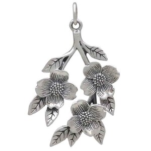 May include: Silver pendant featuring a delicate branch with three stylized flowers and leaves. The flowers have a textured surface and are arranged in a cascading design.