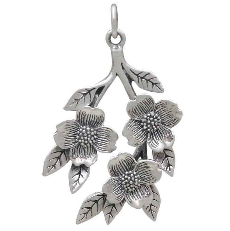May include: Silver pendant featuring a delicate branch with three stylized flowers and leaves. The flowers have a textured surface and are arranged in a cascading design.