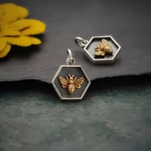 Puede incluir: Dos encantos hexagonales de plata con un diseño de abeja dorada en el interior. La abeja tiene alas y un aguijón.