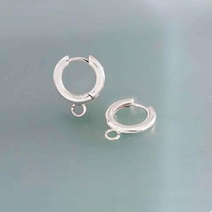 May include: Two silver hoop earrings with a jump ring attached to the bottom of each hoop.