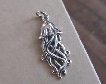May include: A silver-colored jellyfish charm pendant with intricate details. The charm features a bell-shaped top and flowing tentacles, perfect for jewelry making or as a unique accessory. The pendant is shown against a neutral background.