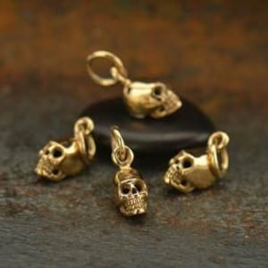 May include: Four gold-toned skull charms with a loop for attaching to a necklace or bracelet.
