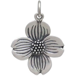 May include: A silver charm in the shape of a dogwood flower. The flower has four petals and a center with a textured design.