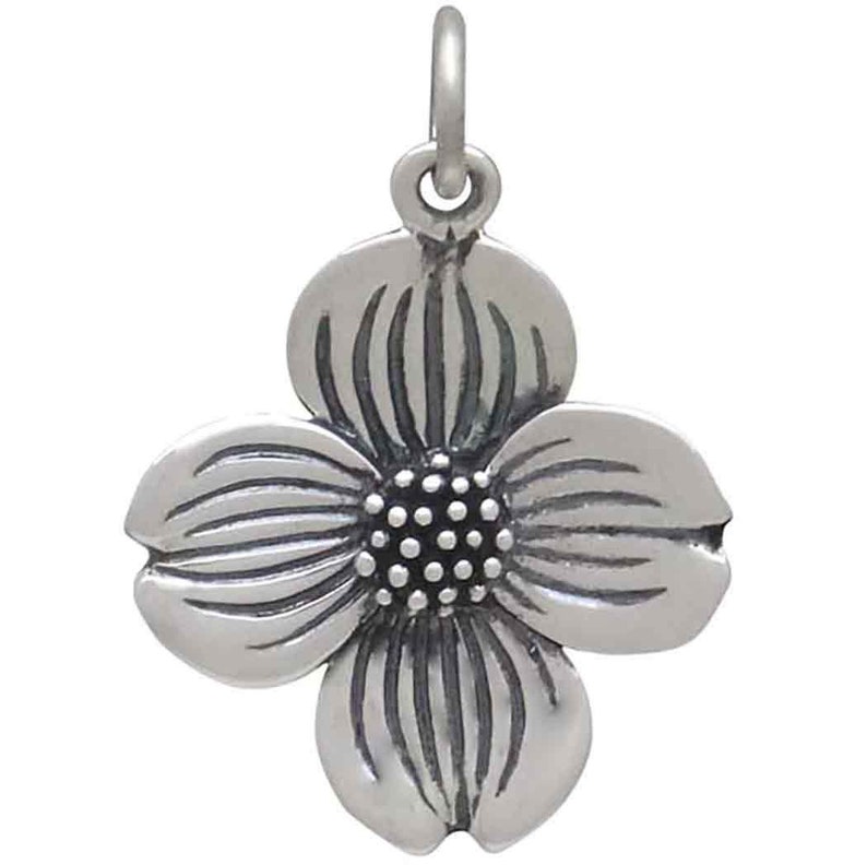 May include: A silver charm in the shape of a dogwood flower. The flower has four petals and a center with a textured design.