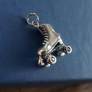 May include: Silver roller skate charm with a detailed design. The charm features a boot with laces and four wheels.