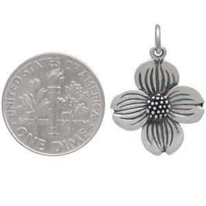 May include: Silver charm in the shape of a dogwood flower. The charm is about the size of a dime.