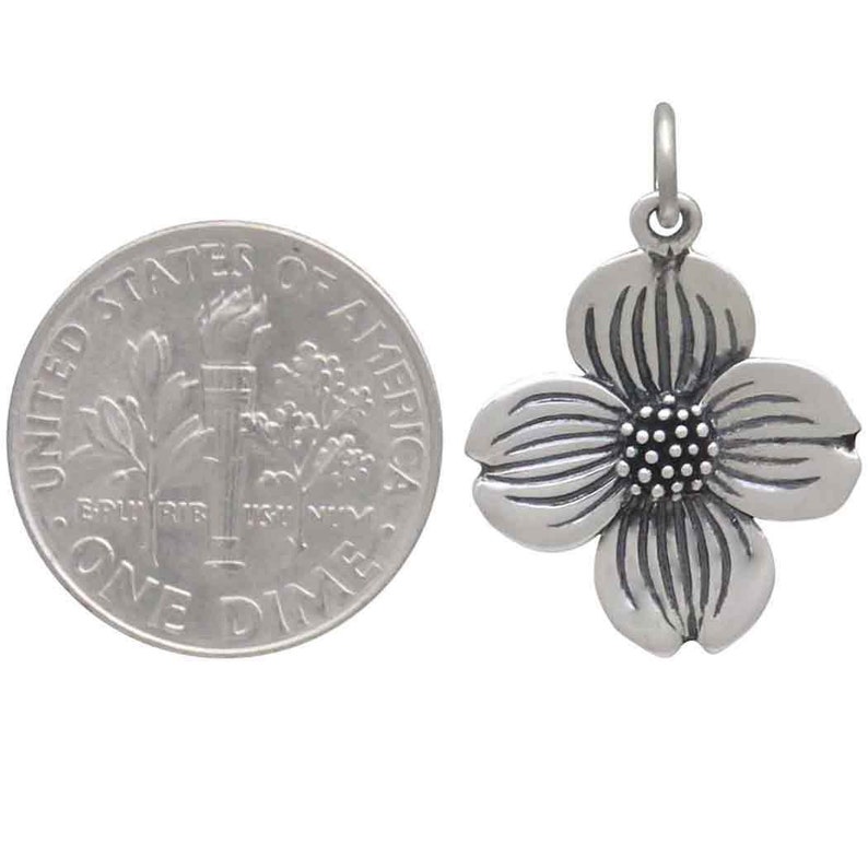 May include: Silver charm in the shape of a dogwood flower. The charm is about the size of a dime.