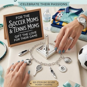 May include: A 925 sterling silver charm bracelet featuring various hobby-themed charms including a soccer ball, tennis racket, kayak, and volleyball. The bracelet is displayed on a stand with a plaque labeled 925 STERLING SILVER HOBBY CHARMS.