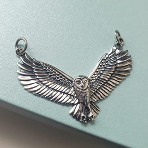 May include: Silver owl pendant with outstretched wings. The owl has a detailed design with a realistic appearance.