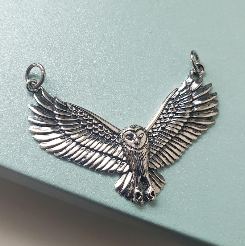 May include: Silver owl pendant with outstretched wings. The owl has a detailed design with a realistic appearance.