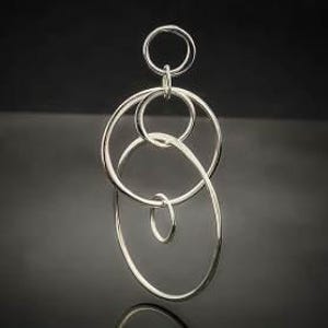 Puede incluir: Pendiente de plata con un diseño de círculos entrelazados de diferentes tamaños.