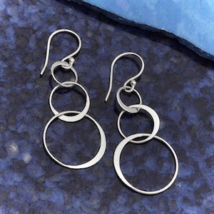 May include: Silver dangle earrings with multiple interlocking circles.