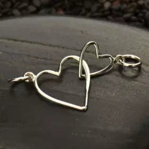May include: Two silver heart-shaped charms, one inside the other, with a jump ring attached to the larger heart.