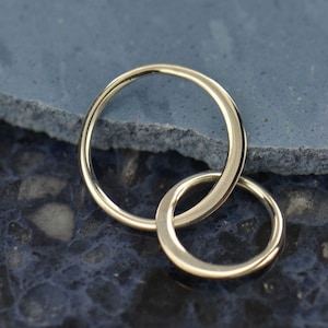 May include: Two interlocking silver rings, one larger than the other, are shown against a blue background.