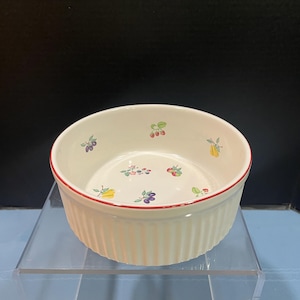 May include: White ceramic baking dish with a red rim and a fruit pattern. The dish has a fluted edge.