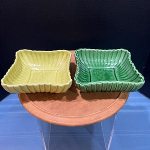 May include: Two square ceramic bowls with fluted edges. One bowl is yellow and the other is green.