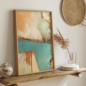 May include: A framed abstract painting with a wooden frame. The painting features a mix of orange, blue, and white colors. The painting is hanging on a wooden shelf.