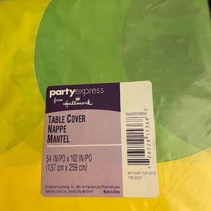 May include: A colorful table cover with green and yellow circular designs. The package includes the text "TABLE COVER" and measurements of 54 inches by 102 inches. The product is from Hallmark's Party Express line.