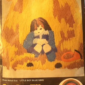 Puede incluir: Un kit de bordado vintage con un diseño de un niño con abrigo azul, rodeado de hilo amarillo y marrón. El kit "Little Boy Blue" mide 15 x 20 cm. Incluye tela de diseño, aguja e instrucciones.