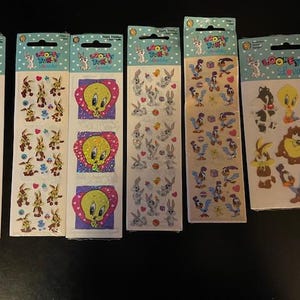 Puede incluir: Seis paquetes de pegatinas con varios personajes de Looney Tunes. Las pegatinas están sobre un fondo blanco con un borde de colores. Los personajes incluyen Piolín, Bugs Bunny, el Pato Lucas y Silvestre el gato.