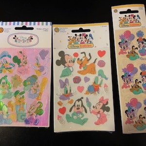 May include: Three sheets of Disney Baby stickers featuring various characters like Mickey Mouse, Minnie Mouse, Donald Duck, and Goofy. The stickers are colorful and have a glossy finish. The stickers are perfect for decorating baby items, scrapbooks, and more.