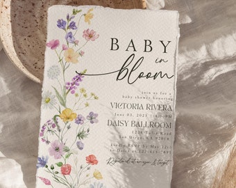 May include: A baby shower invitation featuring a floral design and the text "Baby in Bloom" in a script font. The invitation includes the name Victoria Rivera, the date 03 June 2023, the time 1:00PM, and the location Daisy Ballroom.