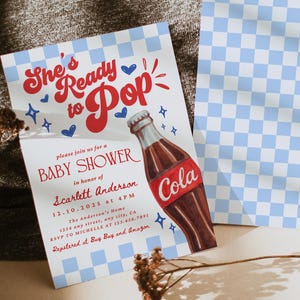 Puede incluir: Invitaci&oacute;n a un baby shower con un dise&ntilde;o retro. La invitaci&oacute;n presenta el texto "She's Ready to Pop" y una ilustraci&oacute;n de una botella de cola. La invitaci&oacute;n incluye los detalles del baby shower y se combina con un patr&oacute;n de cuadros azules y blancos.