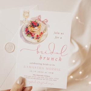Peut inclure: Une invitation &agrave; un brunch de mariage rose et blanc avec une illustration aquarelle d'une assiette de cr&ecirc;pes avec des baies et un verre de champagne. Le texte indique "rejoignez-nous pour un brunch de mariage c&eacute;l&eacute;brant la future mari&eacute;e Samantha Morris 12.10.2024 &agrave; 16h00 The Pancake Palace 1234 any street, any city, any state, 12345 RSVP &agrave; Michelle au 123-456-7891"