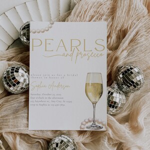 May include: A bridal shower invitation with a pearl and prosecco theme. The invitation is decorated with a glass of prosecco, pearls, and a disco ball. The text on the invitation reads "PEARLS and prosecco" and "please join us for a bridal shower in honor of Sophia Anderson".