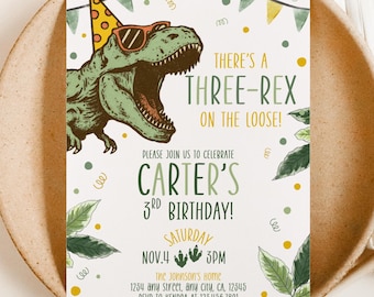 May include: A birthday party invitation featuring a green dinosaur wearing sunglasses and a party hat. The text reads "There's a Three-Rex on the Loose!" and invites guests to Carter's 3rd birthday on November 4th at 3 PM.