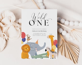 Peut inclure: Une carte d'invitation blanche avec le texte "Wild One" en noir et en écriture cursive. La carte présente une illustration colorée d'un lion, d'un éléphant, d'une girafe, d'un zèbre, d'un singe et d'un crocodile. Le texte sous l'illustration indique "Veuillez vous joindre à nous pour célébrer le 1er anniversaire d'Ashton" avec la date, l'heure et le lieu de la fête.