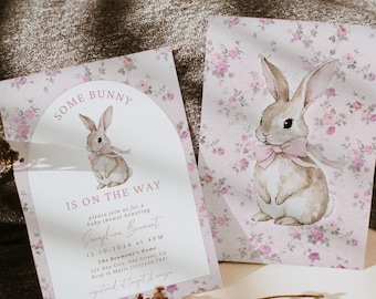 May include: A pink and white baby shower invitation with a floral pattern and a watercolor illustration of a bunny rabbit. The invitation reads "Some Bunny is on the Way" and includes the name "Seraphine Beumont" and the date "12.10.2024".