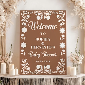Könnte beinhalten: Ein braunes Willkommens-Schild mit weißen floralen Designs und dem Text "Welcome to Sophia & Hernesto's Baby Shower 10.20.2024".