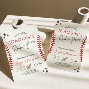 May include: Baseball-themed first birthday party invitation with red and white stitching, stars, and a baseball and bat graphic. The invitation reads "Let's have a ball at Joaquin's Rookie Year. Please join us to celebrate Joaquin is turning one!" with the date and time of the party.