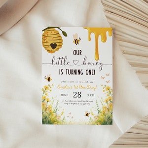 May include: A yellow and white bee-themed baby shower invitation with a honeycomb, dripping honey, and bees. The text reads "Our little honey is turning one!" and "Emilia's 1st Bee-Day!" with the date and time of the party.