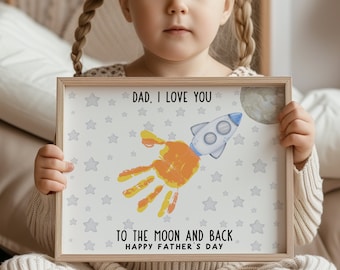 May include: A framed print with a handprint in orange and yellow paint, a rocket, and a moon. The print says "Dad, I love you to the moon and back. Happy Father's Day."