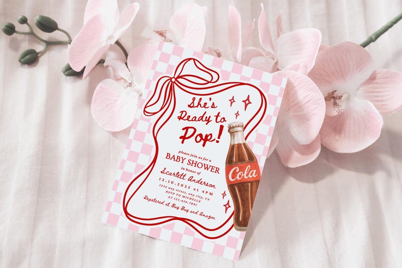 Puede incluir: Una invitaci&oacute;n para baby shower con un dise&ntilde;o retro. La invitaci&oacute;n presenta el texto "She's Ready to Pop!" en rojo, junto con una ilustraci&oacute;n de una botella de cola de dibujos animados. El fondo tiene un patr&oacute;n de cuadros rosas y blancos, y la invitaci&oacute;n est&aacute; rodeada de flores rosas.