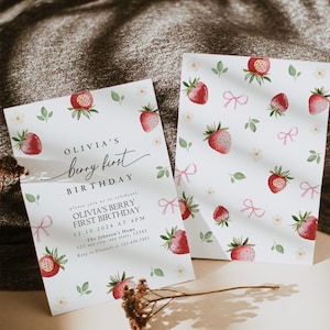 May include: A white invitation card with a strawberry pattern and the text "Olivia's Berry First Birthday" with the date and time of the party. The invitation is for a first birthday party.