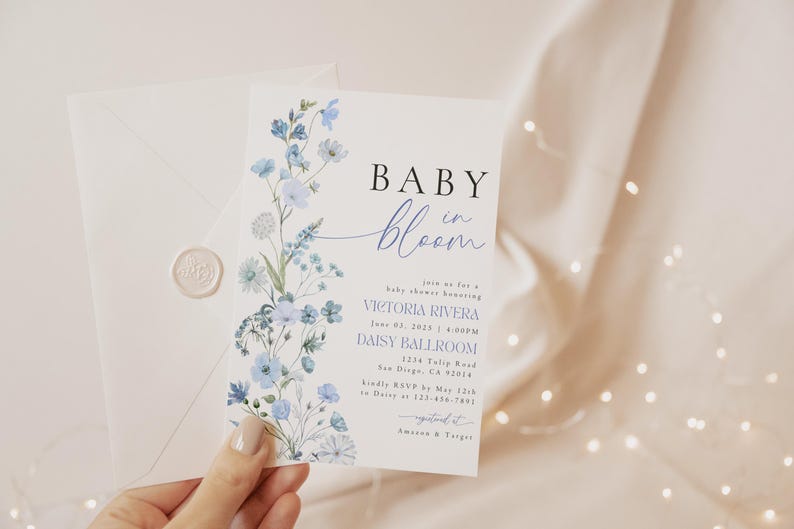 Puede incluir: Una invitaci&oacute;n a un baby shower con un dise&ntilde;o floral de acuarela en tonos azules. La invitaci&oacute;n dice "Baby in Bloom" e incluye los detalles del evento, como la fecha, la hora, el lugar y la informaci&oacute;n de RSVP.