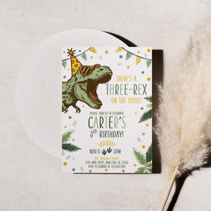 May include: A birthday invitation with a green dinosaur wearing sunglasses and a party hat. The text reads "There's a Three-Rex on the Loose!" and "Carter's 3rd Birthday!" with the date and time.