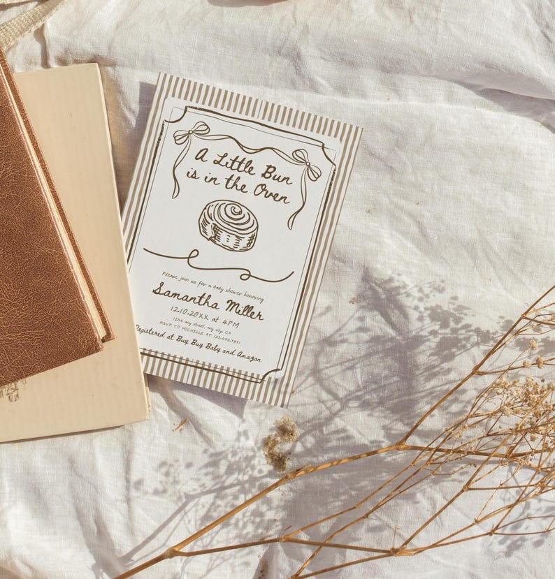 May include: A baby shower invitation with the text "A Little Bun is in the Oven" and a drawing of a bun. The invitation is beige with a striped border and includes the name "Samantha Miller" and event details.